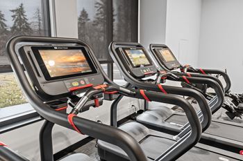 two treadmills in a gym with a large window